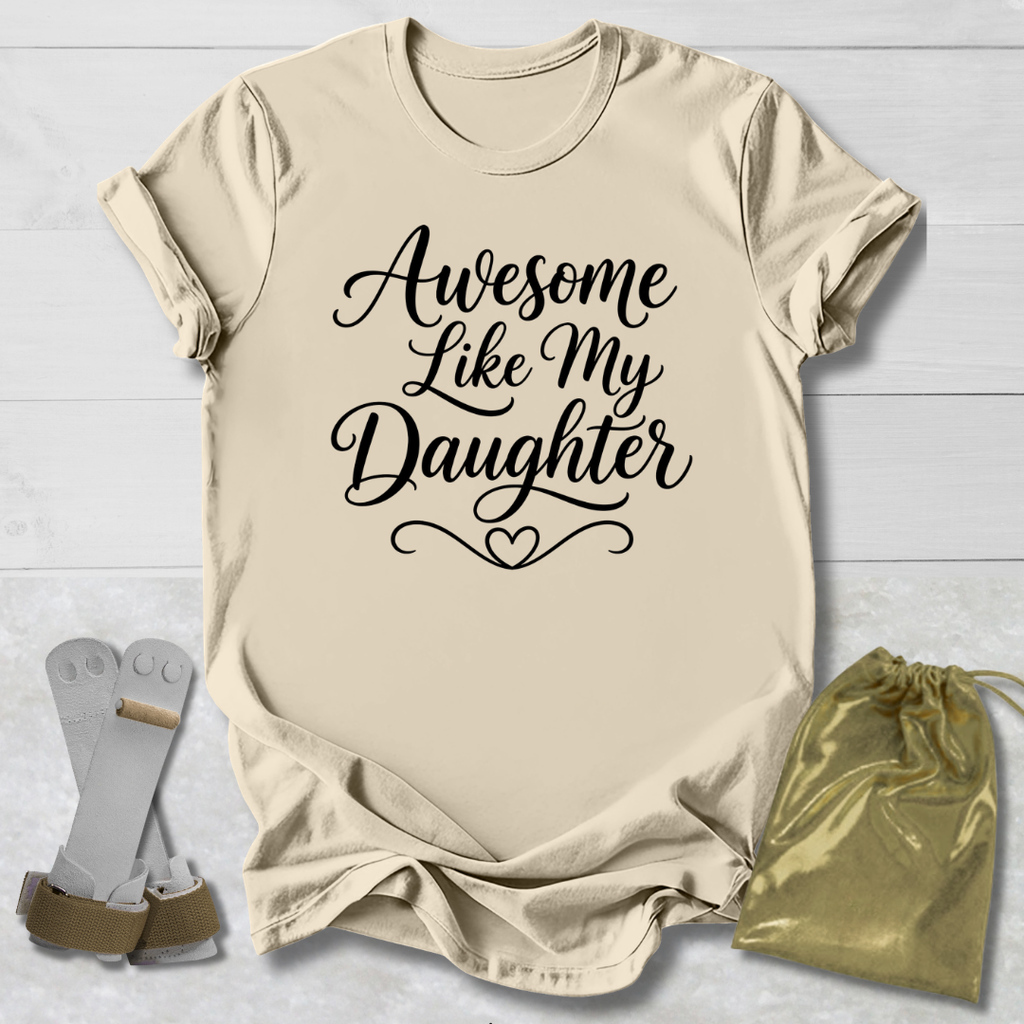 Beige t-shirt with 'Awesome Like My Daughter' text, socks, and drawstring bag on a light wooden surface.