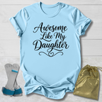 Light blue t-shirt with 'Awesome Like My Daughter' text, socks, and drawstring bag on a light wooden surface.