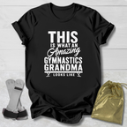 Black t-shirt with text 'This is what an amazing gymnastics grandma looks like' on a wooden surface with socks and a drawstring bag.