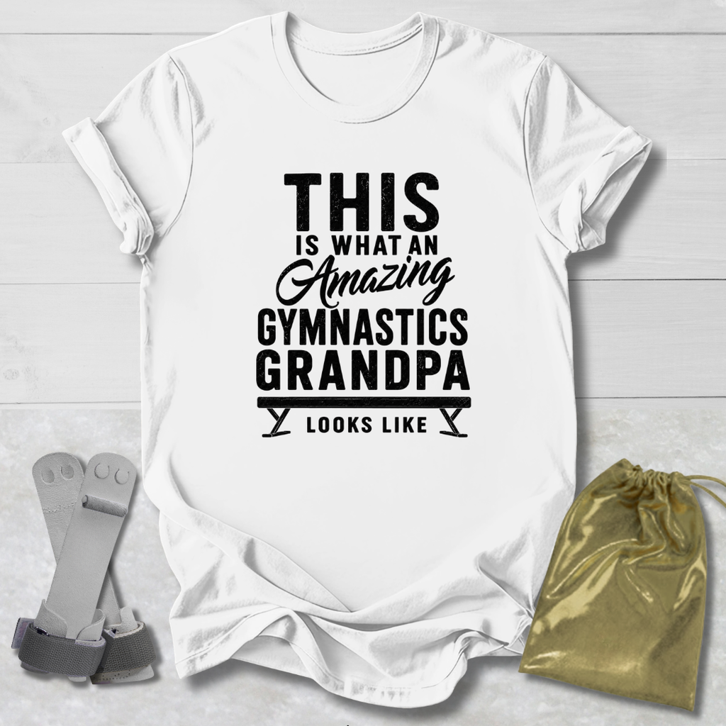 White t-shirt with black text 'This is what an amazing gymnastics grandpa looks like' on a light wooden surface.