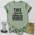 Green t-shirt with text 'This is what an amazing gymnastics grandpa looks like' on a light wooden surface.