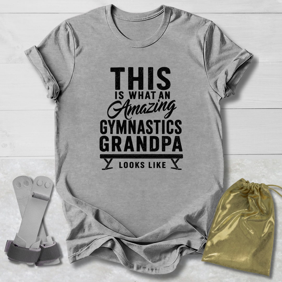 Gray t-shirt with black text 'This is what an amazing gymnastics grandpa looks like' on a light wooden surface.