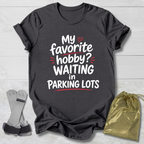 Dark gray t-shirt with humorous text design on a light wooden surface.