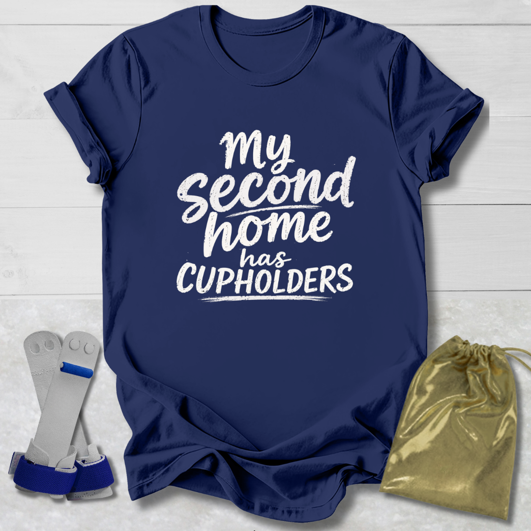 Navy blue t-shirt with white text 'My second home has cupholders' on a light wooden surface with socks and a drawstring bag.