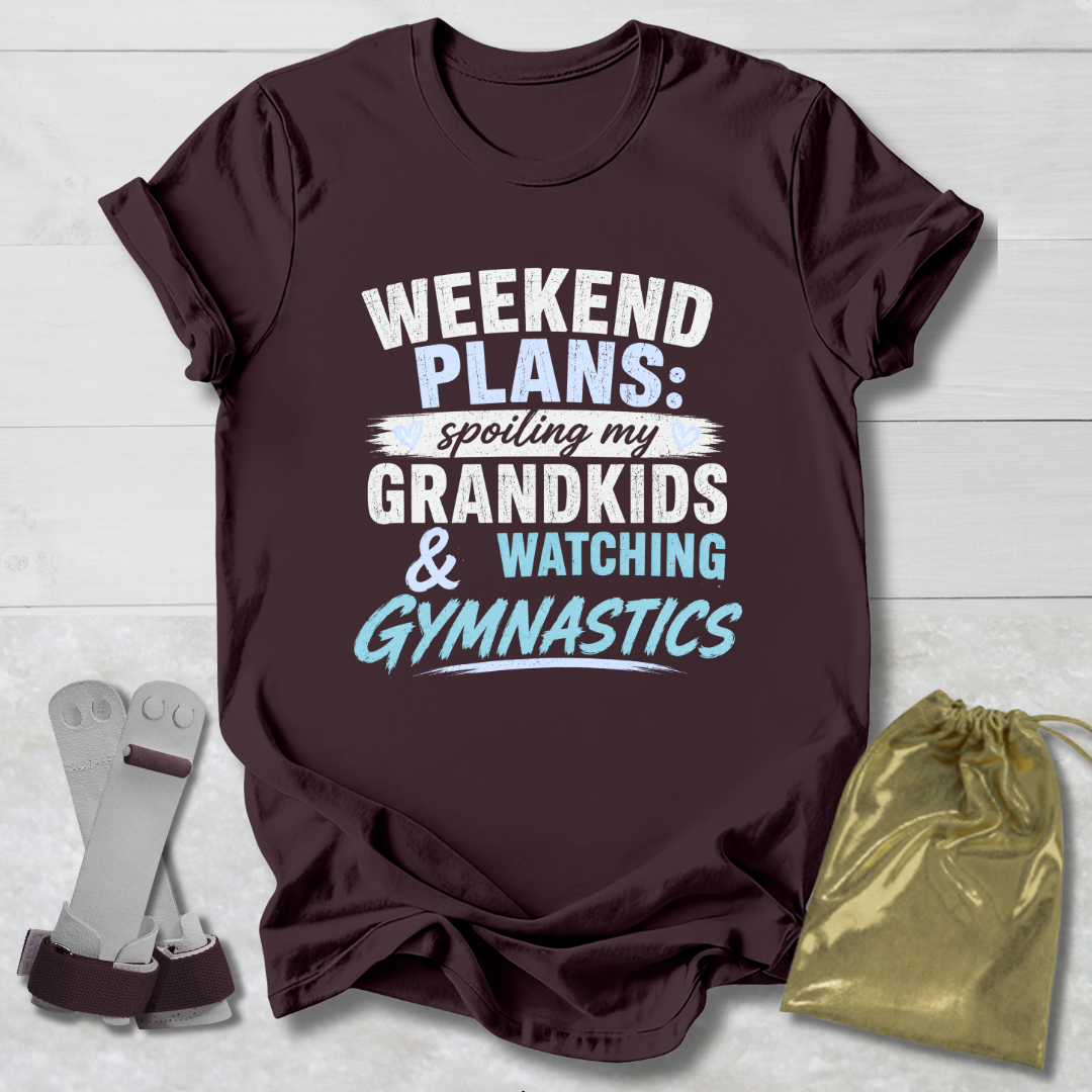 Maroon t-shirt with text 'Weekend Plans: Spoiling my Grandkids & Watching Gymnastics' on a light wooden surface.