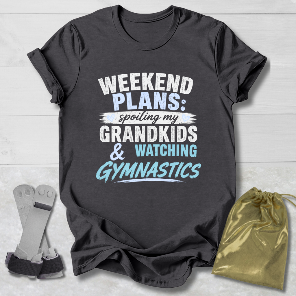 Dark gray t-shirt with text 'Weekend plans: spoiling my grandkids & watching gymnastics' on a light wooden surface.