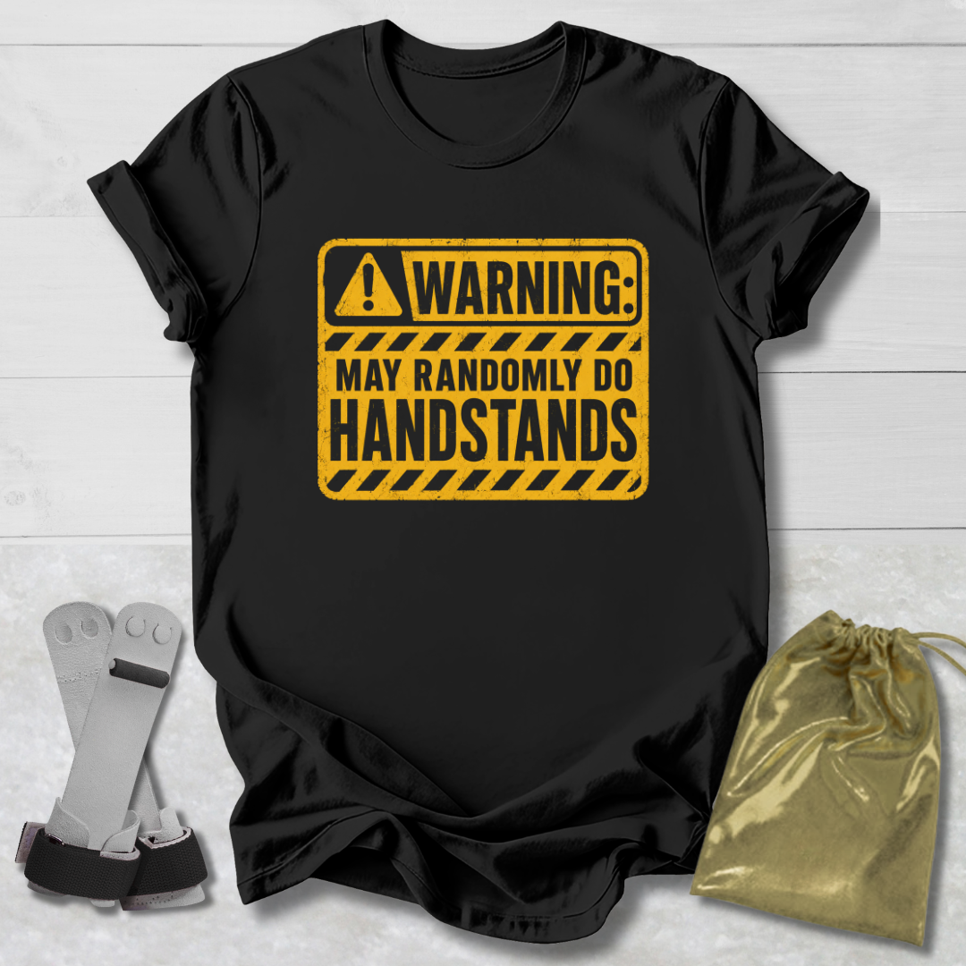 Black t-shirt with yellow warning sign graphic on a light wooden surface.