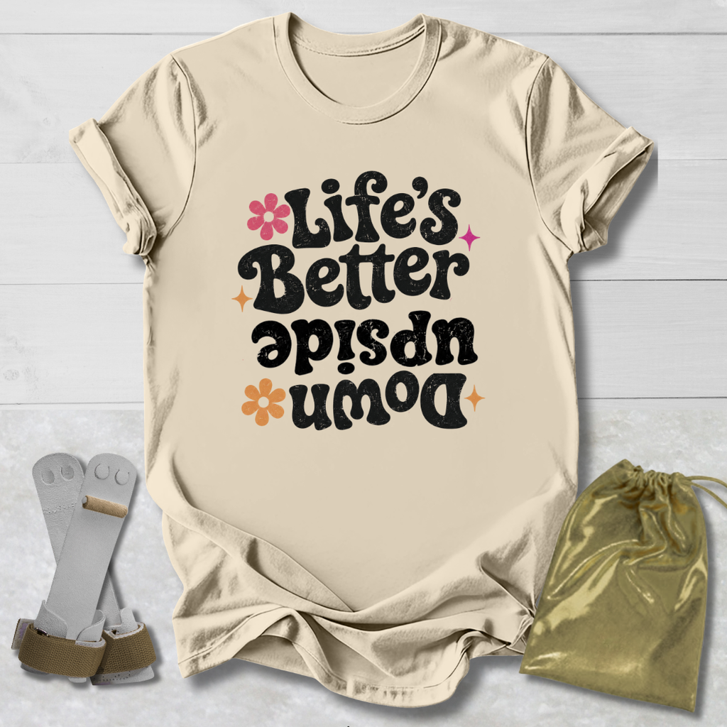 Beige t-shirt with 'Life's Better Upside Down' text, socks, and drawstring bag on a light wooden surface.