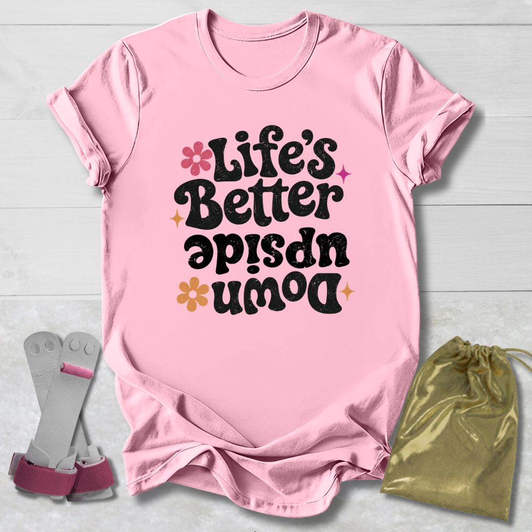 Pink t-shirt with 'Life's Better Upside Down' text, socks, and drawstring bag on a light wooden surface