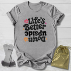 Gray t-shirt with 'Life's Better Upside Down' text, socks, and drawstring bag on a light wooden surface