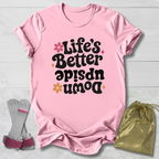 Pink t-shirt with 'Life's Better Upside Down' text, socks, and drawstring bag on a light wooden surface