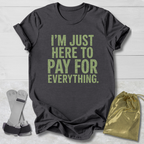 Gray t-shirt with 'I'm just here to pay for everything' text, socks, and drawstring bag on a light wooden surface.