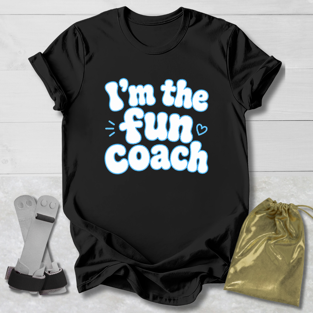 Black t-shirt with 'I'm the fun coach' text on a light wooden surface with socks and a drawstring bag.