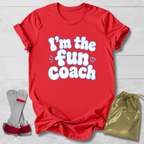 Red t-shirt with 'I'm the fun coach' text, socks, and drawstring bag on a light wooden surface