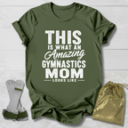 Green t-shirt with text 'This is what an amazing gymnastics mom looks like' on a wooden surface with socks and a drawstring bag.