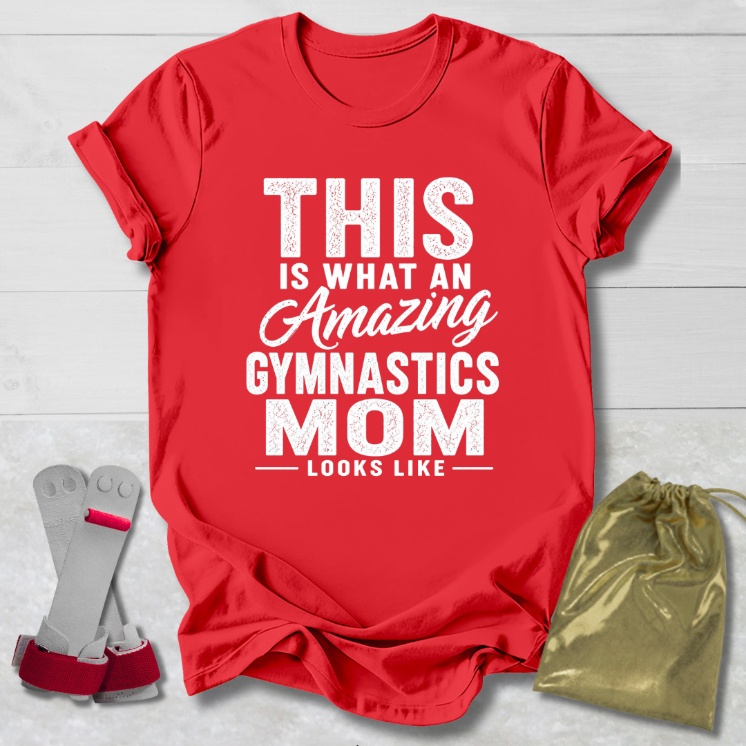Red t-shirt with text 'This is what an amazing gymnastics mom looks like' on a light wooden surface, with socks and a drawstring bag.