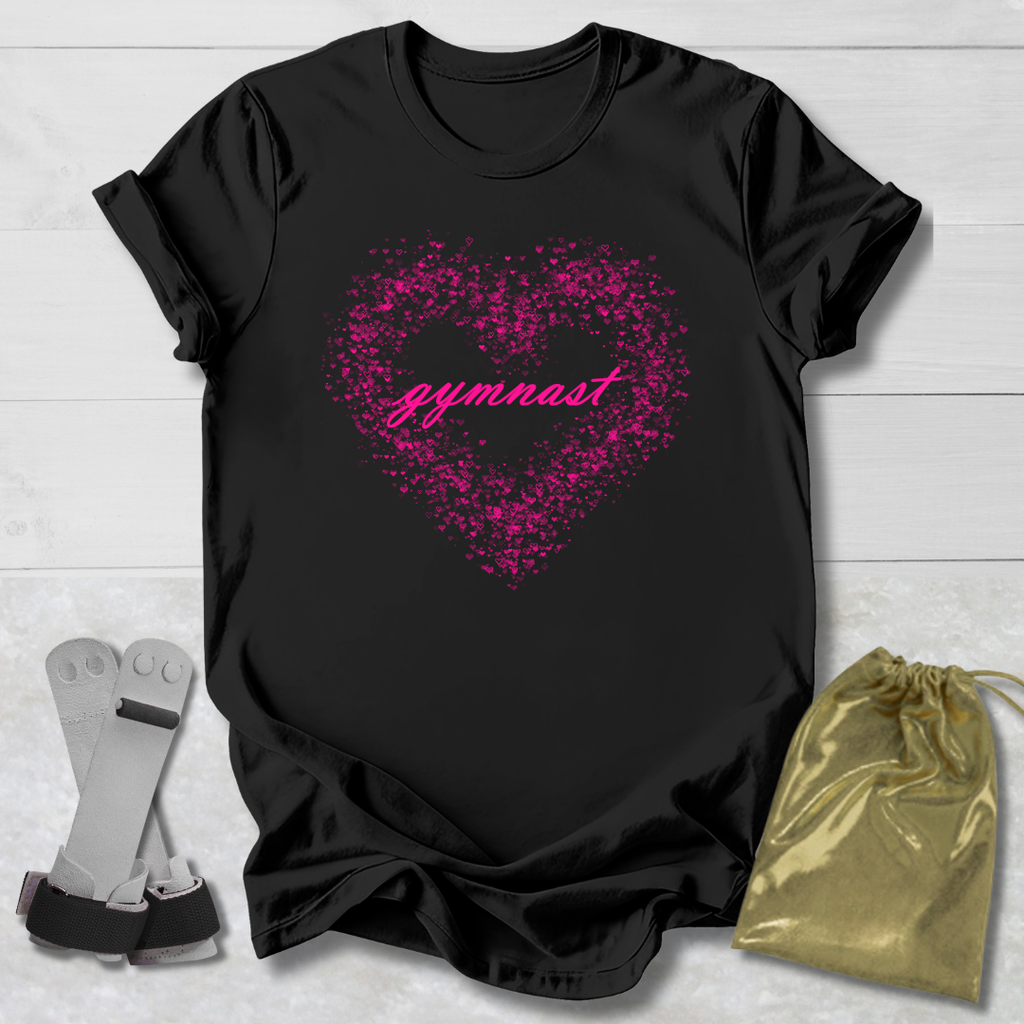 Black t-shirt with pink heart and 'gymnast' text, socks, and gold drawstring bag on a light wooden surface.
