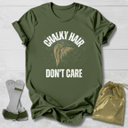 Green t-shirt with 'Chalky Hair Don't Care' text and graphics on a wooden surface.