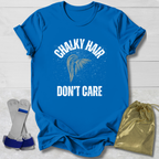 Blue t-shirt with 'Chalky Hair Don't Care' text and graphics on a light wooden surface.