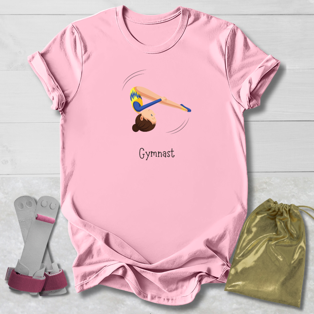 Pink t-shirt with gymnast design and 'Gymnast' text, paired with socks and a drawstring bag on a light wooden surface.