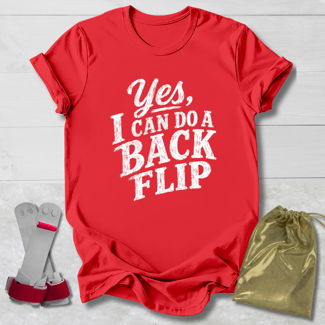 Red t-shirt with 'Yes, I can do a back flip' text, socks, and drawstring bag on a light wooden surface.