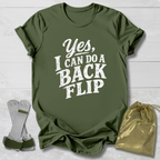 Green t-shirt with 'Yes, I can do a back flip' text on a light wooden surface.