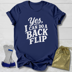 Navy blue t-shirt with 'Yes, I can do a back flip' text on a light wooden surface.