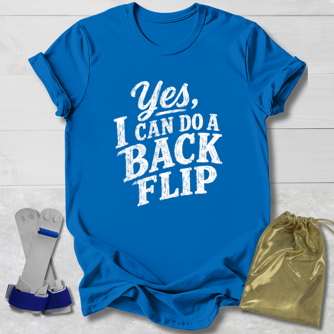 Blue t-shirt with 'Yes, I can do a back flip' text on a light wooden surface with socks and a drawstring bag.
