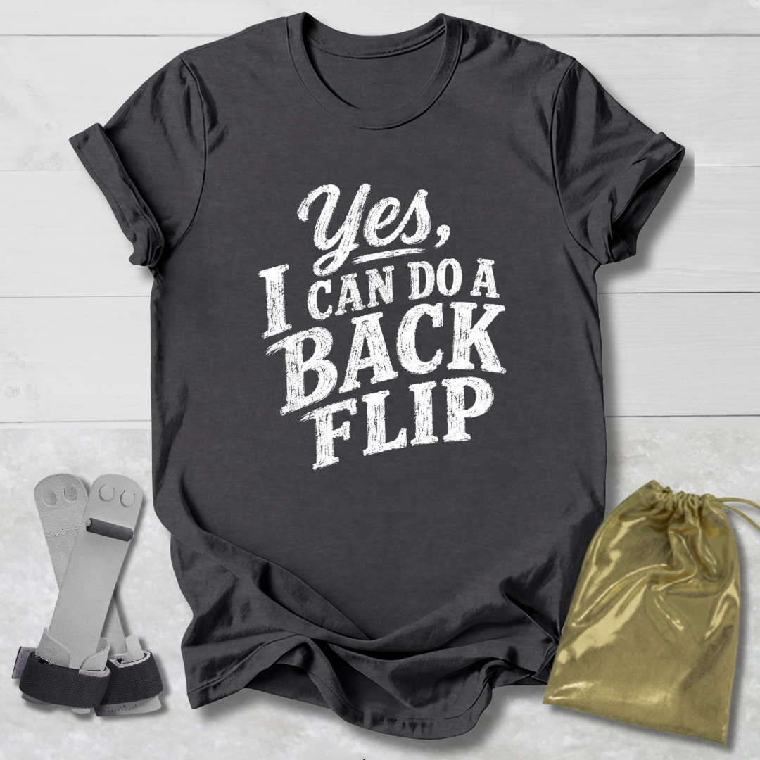 Black t-shirt with 'Yes, I can do a back flip' text on a light wooden surface with socks and a drawstring bag.