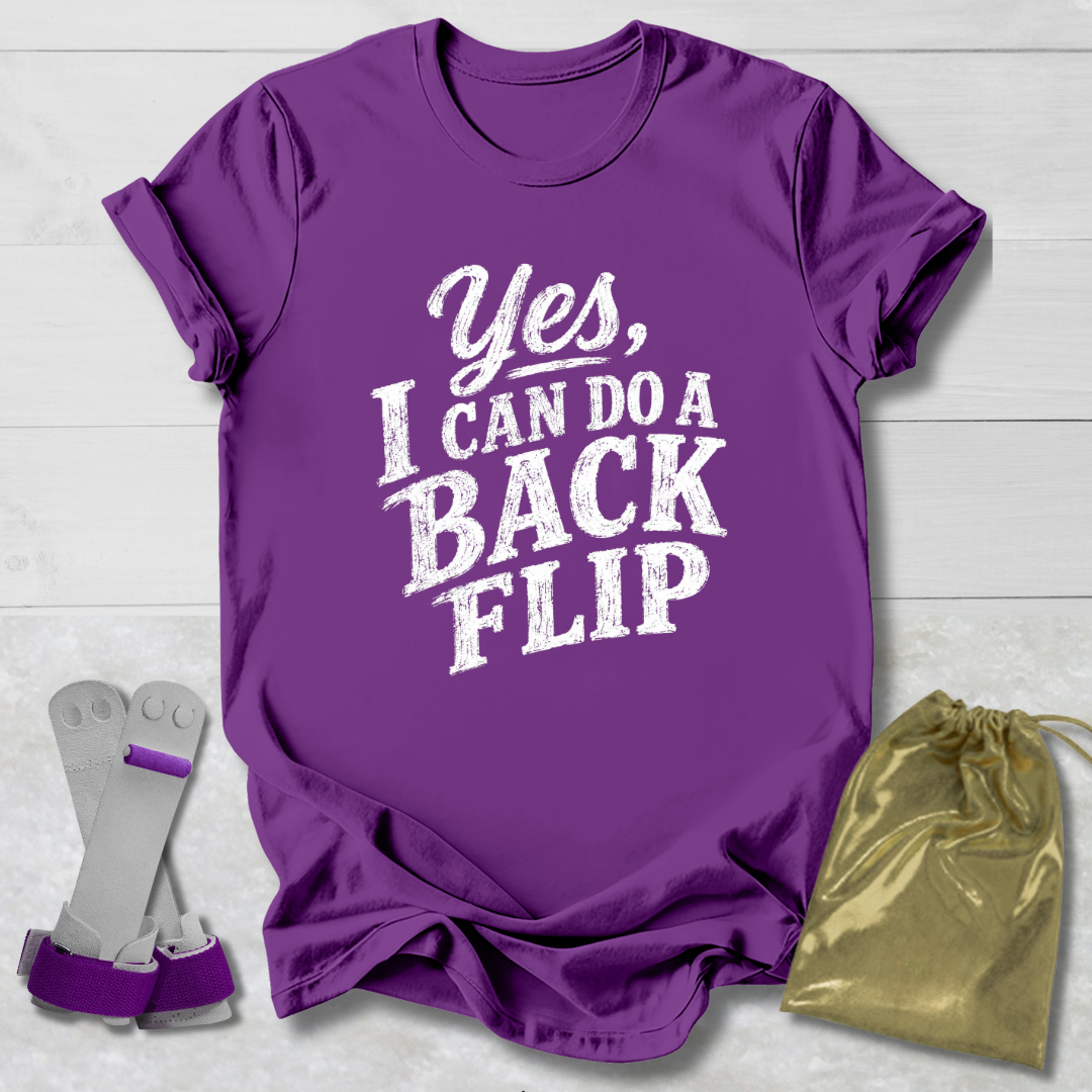 Purple t-shirt with 'Yes, I can do a backflip' text, socks, and drawstring bag on a light wooden surface.