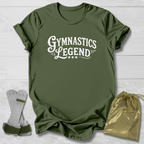 Green t-shirt with 'Gymnastics Legend' text, socks, and drawstring bag on a light wooden surface.
