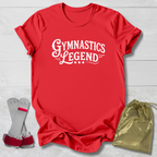 Red t-shirt with 'Gymnastics Legend' text, socks, and drawstring bag on a light wooden surface