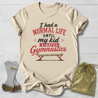 Beige t-shirt with humorous gymnastics text, socks, and drawstring bag on a light wooden surface