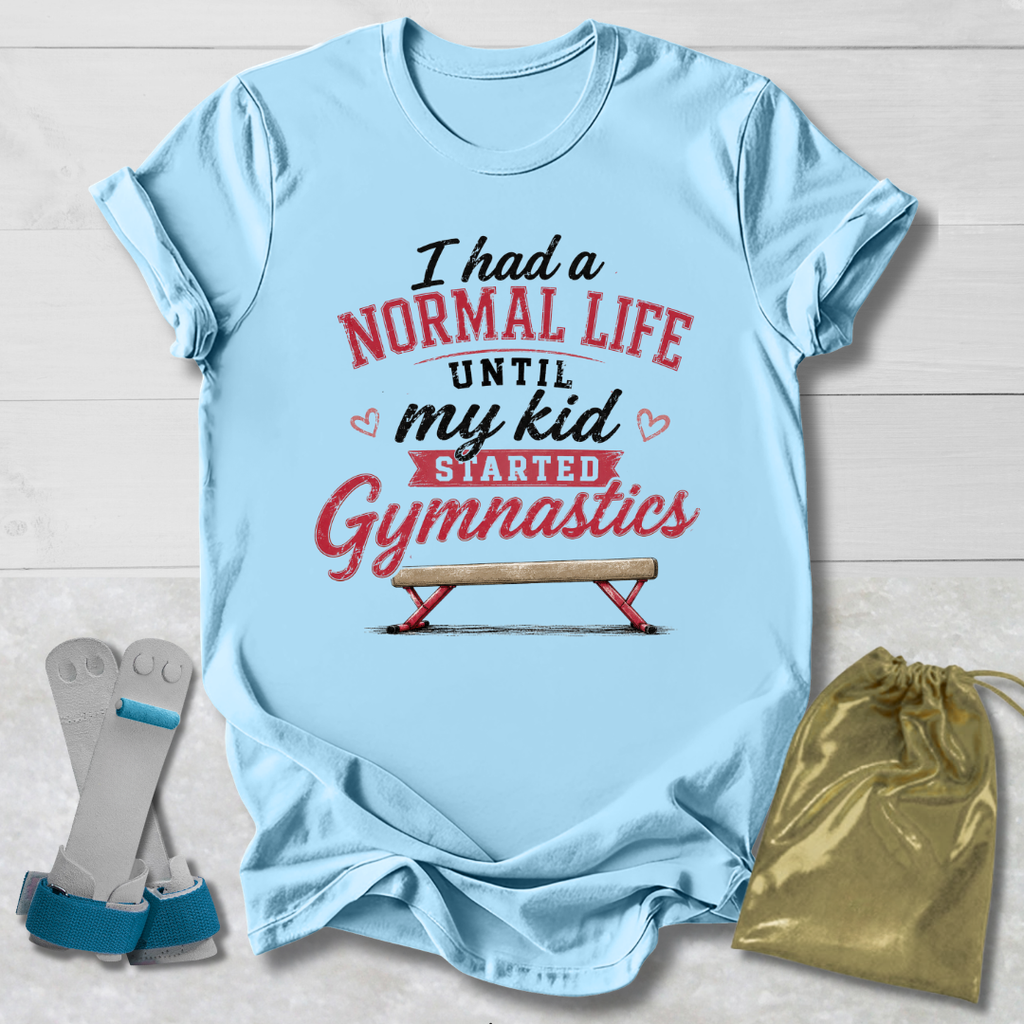 Light blue t-shirt with humorous gymnastics text, socks, and drawstring bag on a wooden surface