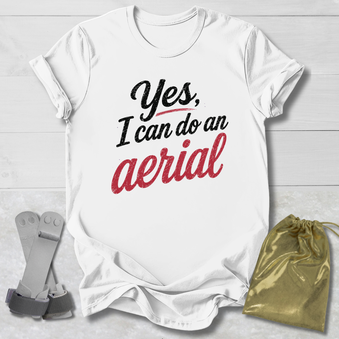 White t-shirt with 'Yes, I can do an aerial' text on a light wooden surface with accessories.