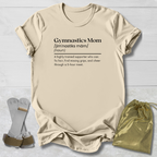 Beige t-shirt with 'Gymnastics Mom' definition text, socks, and drawstring bag on a light wooden surface.