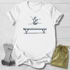White t-shirt with a graphic of a gymnast on a balance beam, paired with socks and a drawstring bag on a light wooden surface.