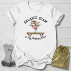 White t-shirt with a graphic of a cat on a balance beam and text, placed on a light wooden surface with socks and a drawstring bag.