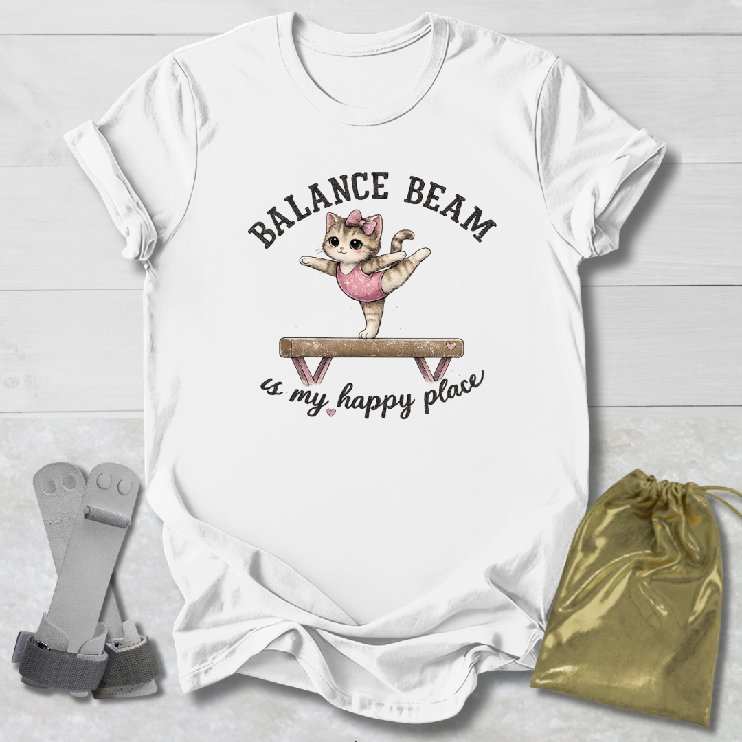 White t-shirt with a graphic of a cat on a balance beam and text, placed on a light wooden surface with socks and a drawstring bag.