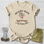 Beige t-shirt with a graphic of a cat on a balance beam and text, placed on a light wooden surface with socks and a drawstring bag.