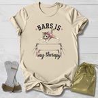 Beige t-shirt with a graphic of a cat on bars and text, socks, and a drawstring bag on a light wooden surface.