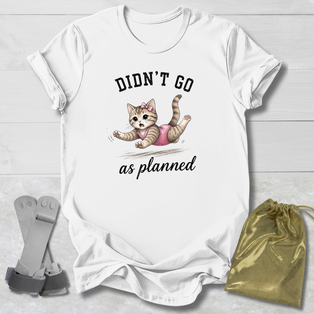 White t-shirt with a cat graphic and text 'Didn't go as planned' on a light wooden surface, with socks and a drawstring bag.