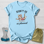 Light blue t-shirt with a kitten graphic and text, socks, and a drawstring bag on a wooden surface.