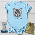 Light blue t-shirt with a cat graphic and text, displayed with socks and a drawstring bag on a light wooden surface.