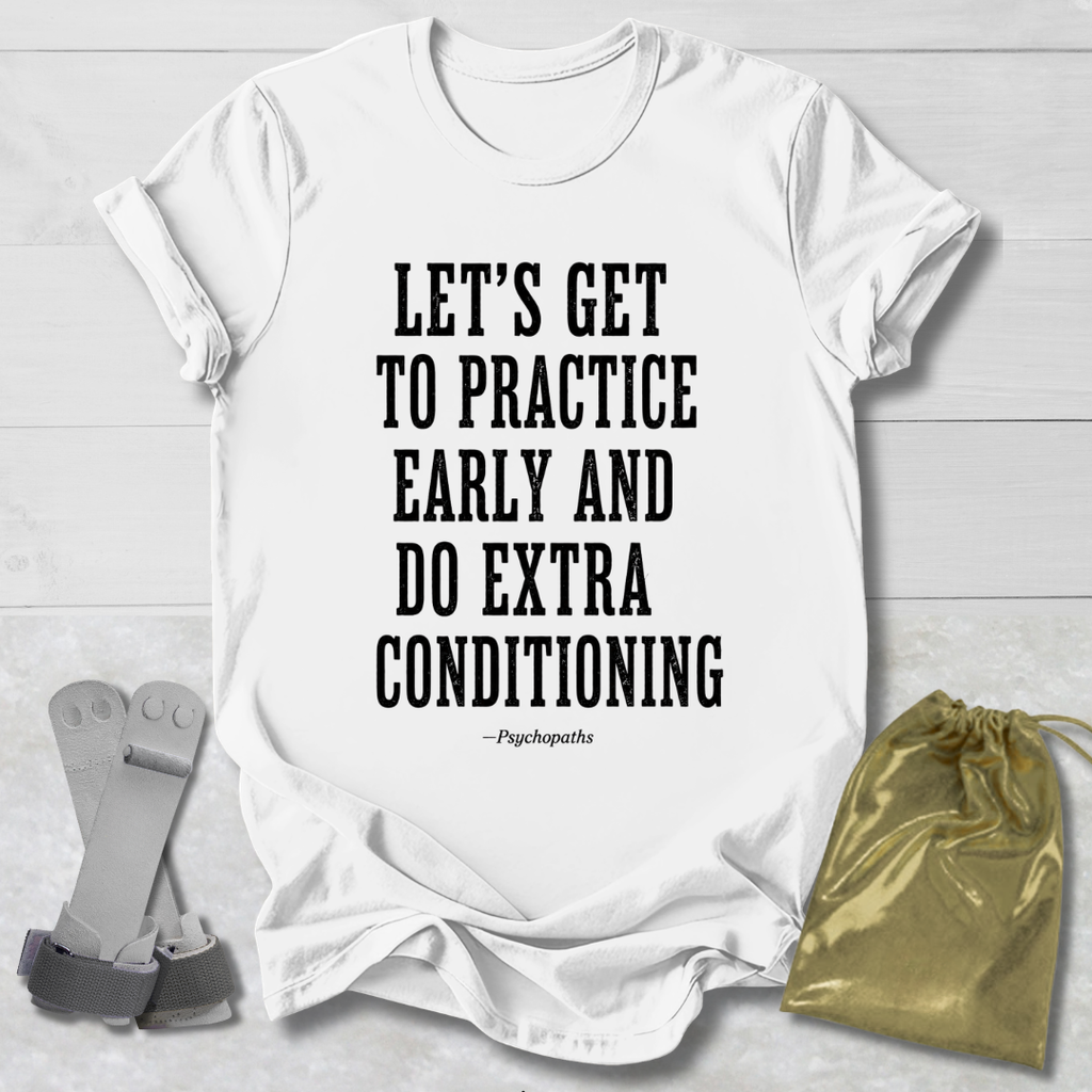A white short-sleeve T-shirt laid flat on a light wood background, printed with the phrase 'LET'S GET TO PRACTICE EARLY AND DO EXTRA CONDITIONING' in large black block letters, with a small '—Psychopaths' line underneath. A gray strap-like prop and a shiny gold drawstring pouch are placed beside the shirt as styling props.