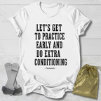A white short-sleeve T-shirt laid flat on a light wood background, printed with the phrase 'LET'S GET TO PRACTICE EARLY AND DO EXTRA CONDITIONING' in large black block letters, with a small '—Psychopaths' line underneath. A gray strap-like prop and a shiny gold drawstring pouch are placed beside the shirt as styling props.