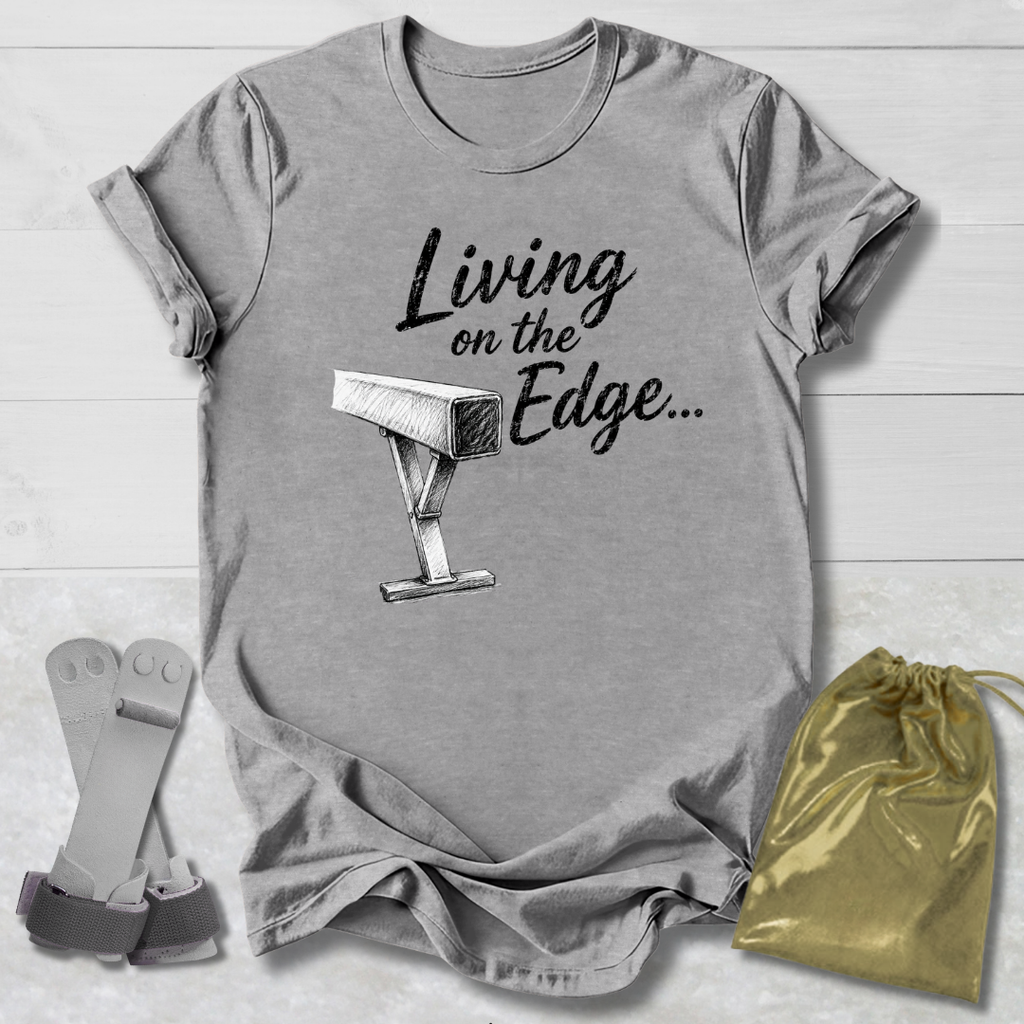 A heather gray graphic T-shirt laid flat on a white wood background, printed with the phrase 'Living on the Edge.