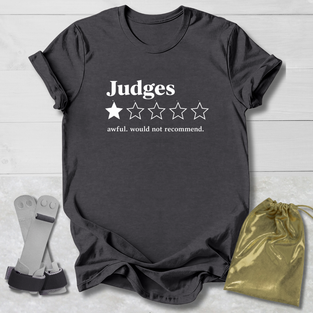 A dark charcoal gray graphic t-shirt laid flat on a white wood background, featuring the word 'Judges' in white above a one-out-of-five star rating graphic with the text 'awful. would not recommend.