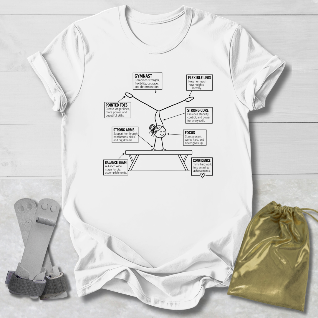 A white graphic t-shirt laid flat on a light wood background, featuring a black line art diagram of a gymnast with labeled body parts and text. A gold drawstring bag and gray straps are placed beside the shirt as styling props.