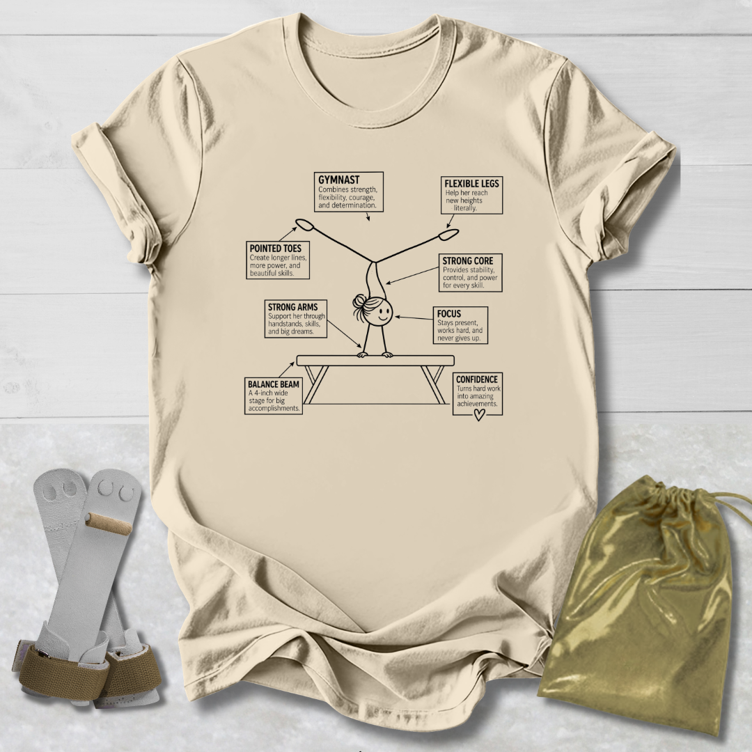 A beige graphic t-shirt featuring a gymnast diagram with labeled body parts, styled in a flat lay on a white wood background alongside a pair of gymnast straps and a gold drawstring bag.